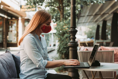 Woman using phone while sitting on table