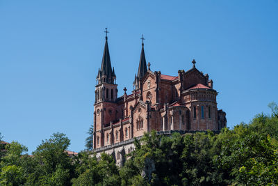 Basílica de santa maría la real de covadonga on the hill surrounded by the greenery