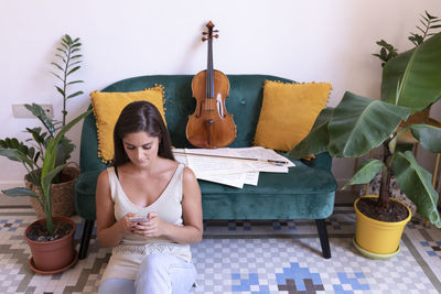 Young woman sitting on potted plant