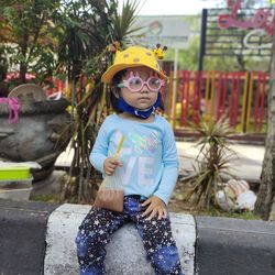 Cute girl wearing eyeglasses while sitting outdoors