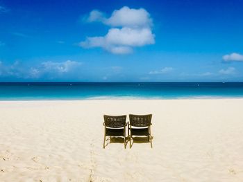 Chair on beach against sky