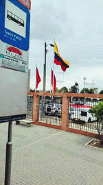 Flag sign on pole by building against sky