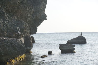 Rocks on sea against clear sky