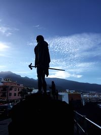 Silhouette man standing on city against sky