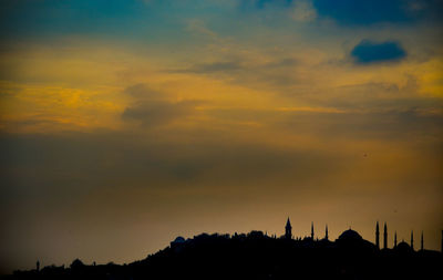 Silhouette trees and buildings against sky during sunset