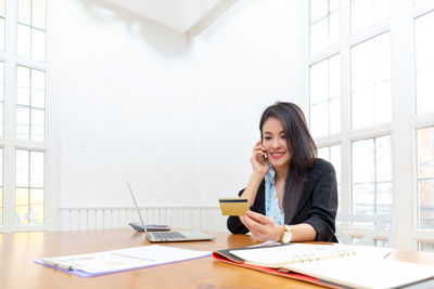 Young woman using phone while sitting on table