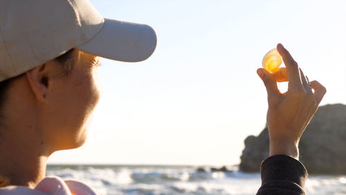 Close-up of woman holding seashell against clear sky