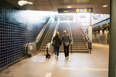 Full length rear view of young couple walking towards staircase at subway station