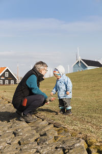 Side view full length of grandfather with granddaughter on field