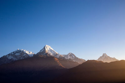 Scenic view of snowcapped mountains against clear blue sky