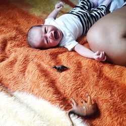 High angle portrait of baby girl crying on bed at home