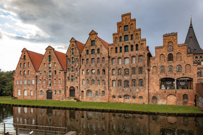 Reflection of old building in canal against sky