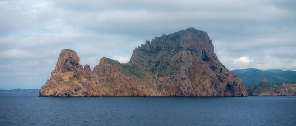 Scenic view of sea and mountain against cloudy sky