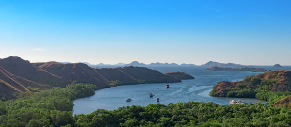 Scenic view of sea and mountains against clear blue sky