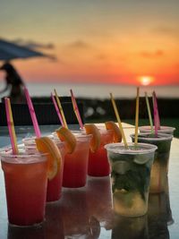 Close-up of drink on table at beach against orange sky