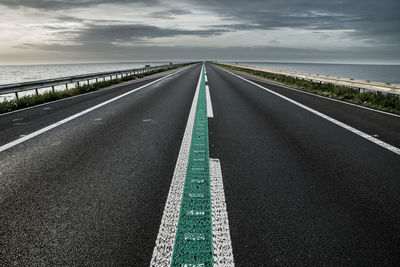 Empty road against cloudy sky during sunset