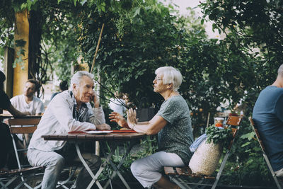 Group of people sitting on table against trees