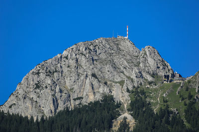 Low angle view of rocky mountains against clear blue sky