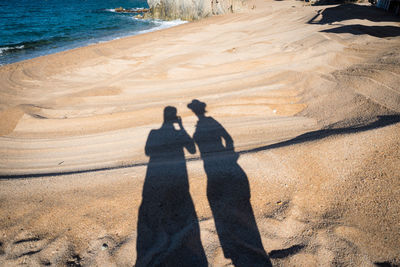 Shadow of people on sand at beach