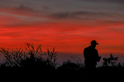 Rear view of silhouette man standing against sky at sunset