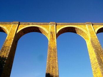 Low angle view of arched structure against blue sky