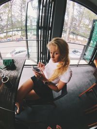 Woman using mobile phone while sitting in cafe