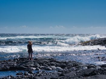 Full length of man standing on rock at beach against sky