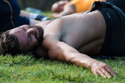 Shirtless man lying down on grassy field