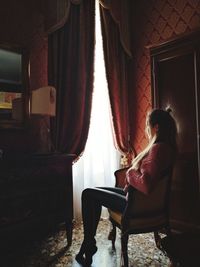 Side view of woman sitting on chair at home