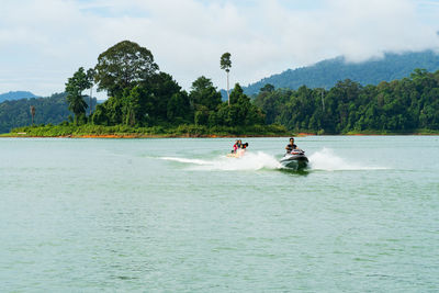 People riding motor boat against sky