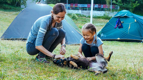 Mother and daughter playing dog on grassy land