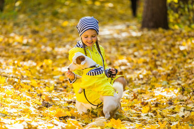 Low section of woman with yellow autumn leaves