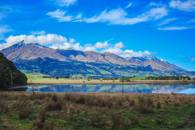 Scenic view of lake and mountains against blue sky