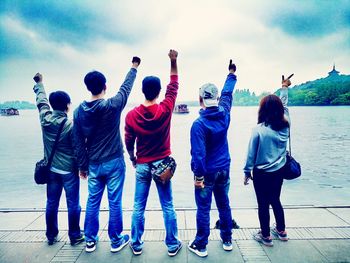 Rear view of people with umbrellas against sky