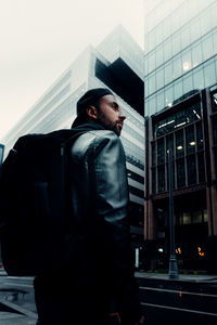 Low angle view of man looking at modern building in city