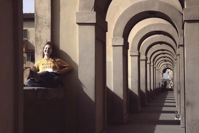 Woman sitting in corridor of building