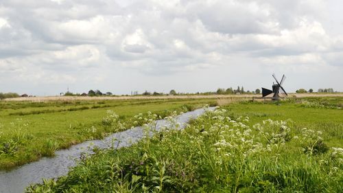 Scenic view to typical landscape of netherlands with fields, water canal and little windmill