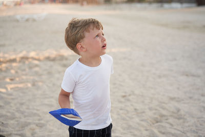 Boy looking away while standing on beach