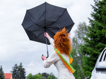 Woman holding umbrella while standing outdoors