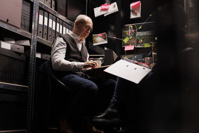 Rear view of man using digital tablet while sitting in office