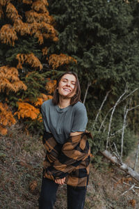 Portrait of smiling young woman standing in forest