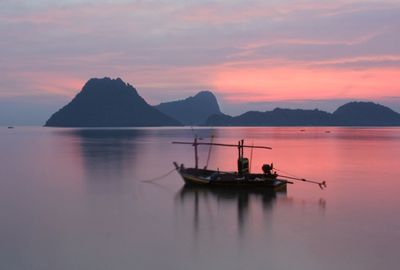 Fishing boat in sea against sky during sunset