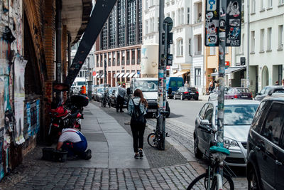 Rear view of woman walking on sidewalk in city