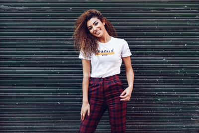 Portrait of smiling young woman standing against brick wall