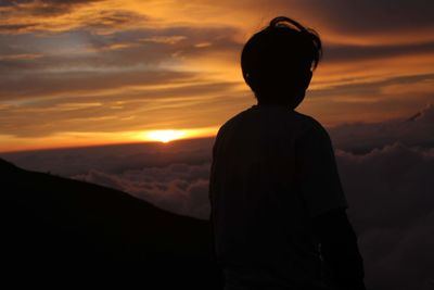 Rear view of silhouette man standing against sky during sunset