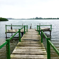 Wooden pier over lake against clear sky