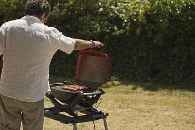 Rear view of man barbecuing sausages