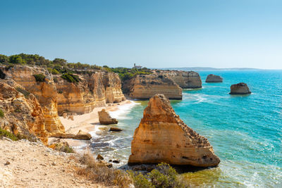 Rock formations in sea against clear blue sky