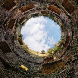 Low angle view of trees against sky seen through hole