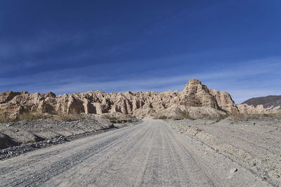 Road by desert against blue sky